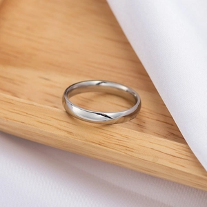 Polished silver stainless steel ring displayed on wood and white silk fabric