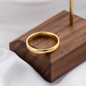 Macro shot of 18k gold plated titanium steel ring on walnut stand with white silk