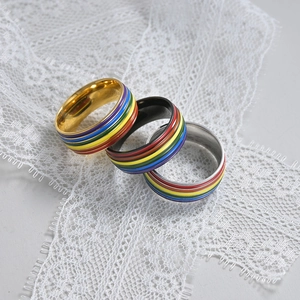 Close-up of rainbow enamel striped rings in gold, black and silver on white lace