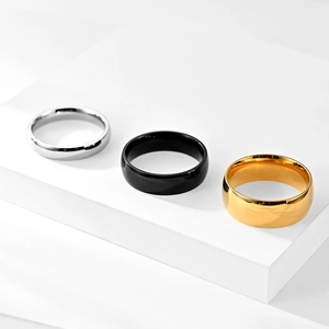 Polished titanium steel rings in silver, black, and gold finish on a geometric stand