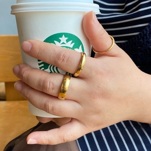 Close-up of three stackable polished gold titanium rings worn on a hand in daily life