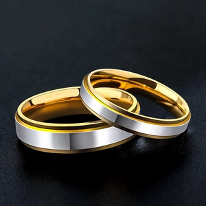 Polished silver and gold two-tone tungsten steel couple rings on a sleek black background