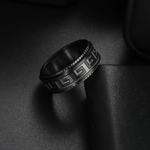 Gros plan de la bague rotative noire anti-stress avec motif grec sur fond sombre