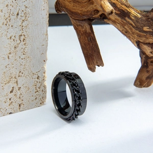 Detalle de anillo giratorio vikingo negro con runas nórdicas sobre piedra y madera