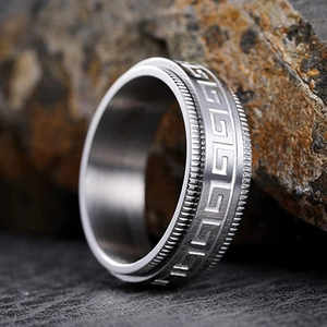Bague anti-stress rotative en acier avec motif grec sur fond de roche sombre