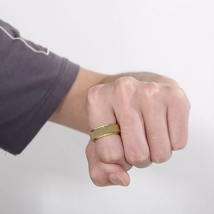 Detail van gouden mesh-textuur op een brede titanium stalen spinnerring aan de hand