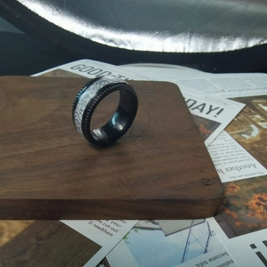 Detail of black stainless steel ring featuring silver meteorite inlay and textured edges