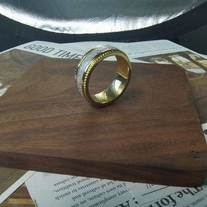 Detail of two-tone gold and silver brushed titanium steel ring on a dark wooden stand