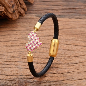 Boho Lederarmband mit Puzzle-Anhänger und rosa Zirkon-Besatz auf Holzuntergrund