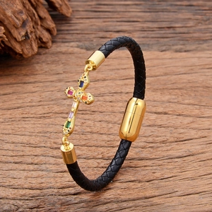 Close-up of black braided leather bracelet with golden cross and magnetic buckle on wood