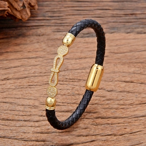 Bracelet en cuir tressé noir avec breloque infini dorée sur un support en bois