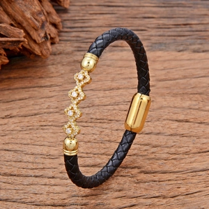 Vue macro détaillée du bracelet en cuir tressé noir avec charmes dorés et zircons blancs