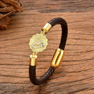 Brown braided leather bracelet with gold snake coin charm on weathered wood background