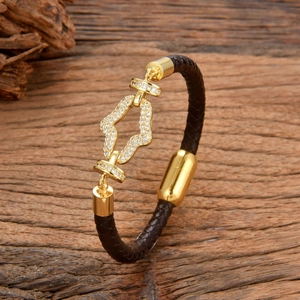 Braided dark brown leather bracelet with gold geometric zircon inlay on wooden table