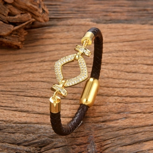 Braided leather bracelet with gold geometric diamond-encrusted centerpiece on wood
