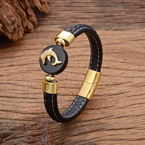 Handmade woven leather bracelet with gold dolphin charm and magnetic clasp on wood