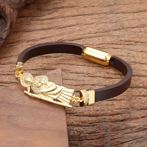Détail du bracelet en cuir tressé marron foncé avec médaillon religieux doré et zircon