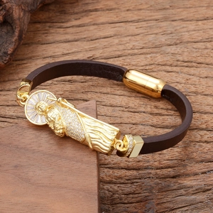 Détail du bracelet en cuir tressé religieux avec icône de saint doré et zircons blancs