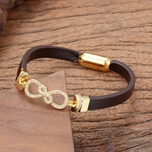 Detailed macro view of dark brown braided leather bracelet with golden infinity charm