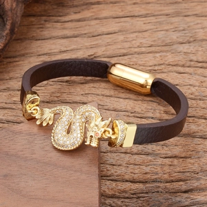 Men's leather bracelet with golden dragon charm and crystals on a natural wood background