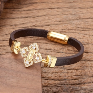 Close-up of golden religious medal with white stones on a brown leather bracelet