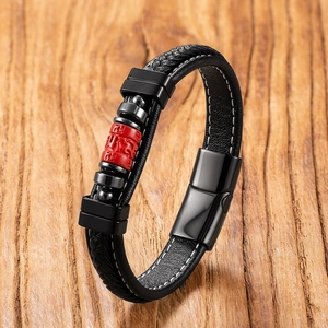Macro view of braided leather cord bracelet with red cinnabar lotus charm and magnetic clasp