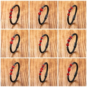 Detailansicht von neun geflochtenen Lederarmbändern mit roten Zinnoberperlen und Magnet