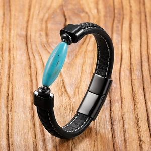 Detail of black leather bracelet featuring white stitching and turquoise stone bead