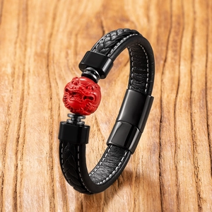 Detail of hand-woven black leather bracelet with red cinnabar bead and black steel clasp