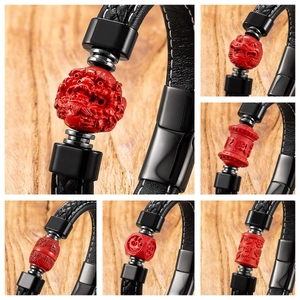 Detailed view of hand-woven black leather bracelet with red carved cinnabar charms and lion head