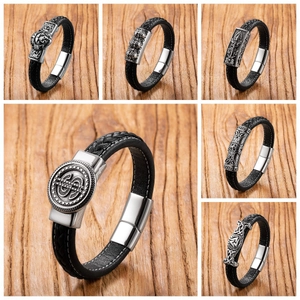 Detail of men's black braided leather bracelets with vintage silver lion and skull charms