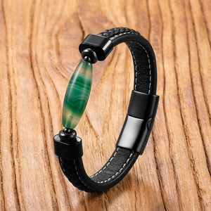 Men's leather bracelet with green agate stone and black metal clasp on wood background