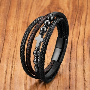 Detailed close-up of multilayer leather bracelet with silver cross and magnetic clasp