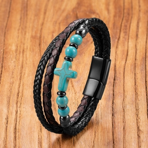 Detail eines mehrlagigen Lederarmbands mit Türkisperlen und einem Kreuzanhänger