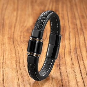 Dettaglio di bracciale in pelle intrecciata con chiusura magnetica su legno rustico