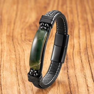 Men's braided leather bracelet with green gemstone and black magnetic clasp on wood