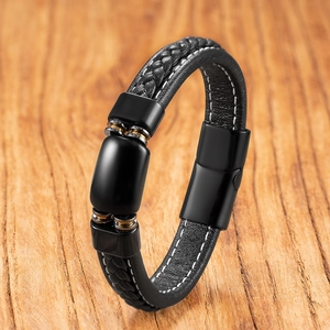 Detail of black braided leather bracelet with magnetic clasp on a wood background