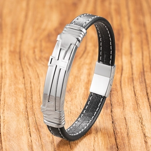 Gevlochten herenarmband van zwart leer met kruis hanger op rustieke houten achtergrond