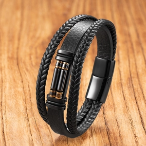 Detail of multi-layer black braided leather bracelet with golden metal accents and magnetic clasp