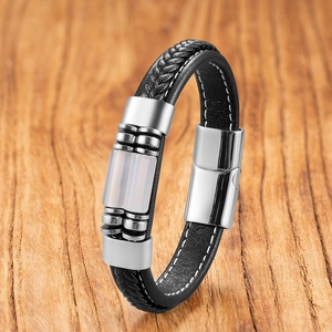 Detail of black braided leather bracelet with stainless steel magnetic clasp on wood