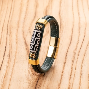 Macro detail of dark green woven leather bracelet with geometric bead and magnetic clasp