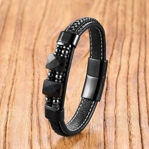 Vue macro d'un bracelet multicouche en cuir tressé noir avec fermoir magnétique sur bois