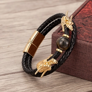 Detail of double-layer black braided leather bracelet with golden dragon heads and tiger eye stone