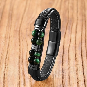 Detail eines mehrlagigen schwarzen Lederarmbands mit grünen Tigerauge-Perlen und Magnetverschluss