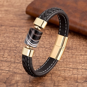 Dettaglio di un bracciale in pelle intrecciata nera con pietra d'agata e accenti in metallo dorato