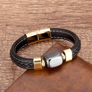 Dettaglio di un bracciale in pelle nera intrecciata da uomo con chiusura magnetica oro