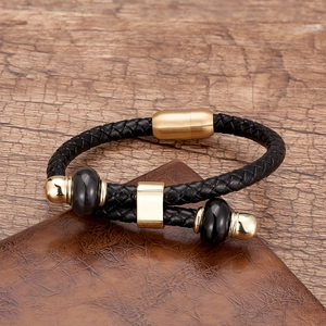 Detail van zwarte gevlochten leren armband met gouden magneetsluiting en metalen kralen