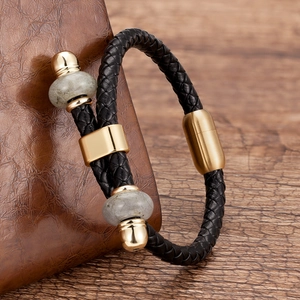 Detail van de gevlochten leren armband met gouden magneetsluiting en grijze stenen kralen