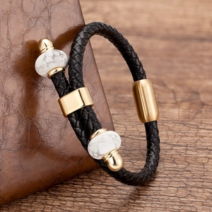 Macro-opname van zwart gevlochten lederen armband met gouden magneetsluiting en marmeren kralen