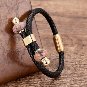 Detail van herenarmband met dubbele laag zwart leer, gouden magneetsluiting en roze stenen
